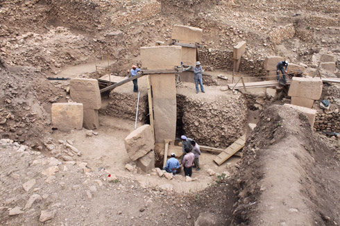 Figure 1: Excavators uncover one of many circular enclosures at Gobekli Tepe. Two large T-shaped pillars over 5m (16 feet) high typically stand in the middle of the ring with smaller pillars facing them. Some of these stones are decorated with reliefs of animals that once lived in the area. This area known as Enclosure D features birds, while others emphasize animals such as snakes, foxes, boars, or wildcats.