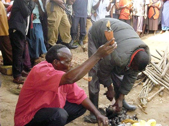 The healer reveals a witchcraft item 'found' in the accused man's house to the crowd. It probably came from the pockets of his assistant's padded jacket.