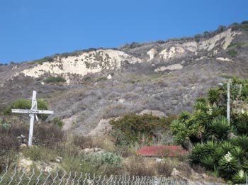 The landslide debris covering the town as of 2011, with the makeshift graves and memorials still standing from 2005. (Courtesy 2011 K. Allison Lenkeit Meezan • Foothill College, Department of Geography • About the Virtual Field Trip  This work is licensed under a Creative Commons Attribution-NonCommercial-ShareAlike 3.0 Unported License.)